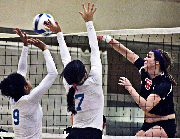 Stephanie Kipp blasts a ball past two Cuyahoga defenders in the second set of today's win. Photo by Nicholas Huenefeld/Owens Sports Information