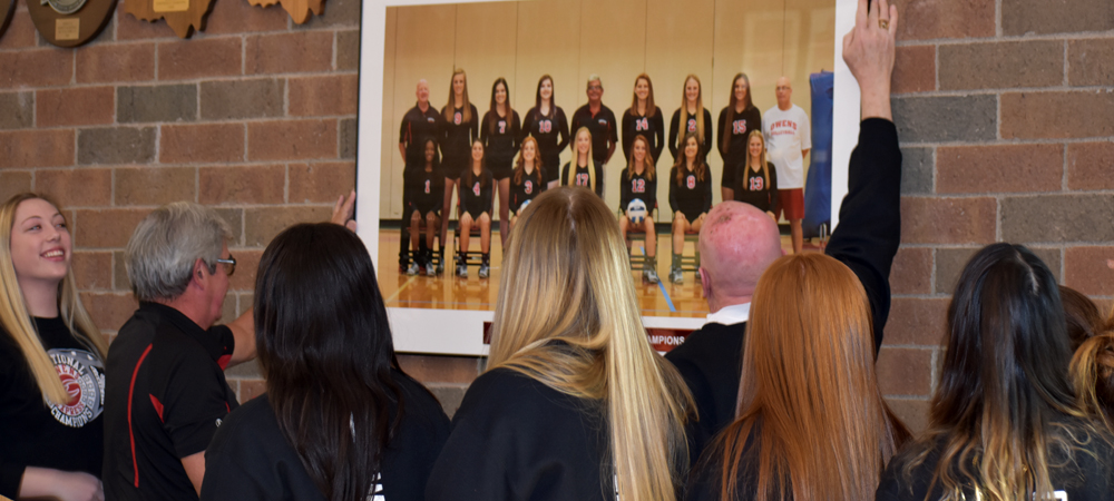 Head Coach Sonny Lewis and assistant Denny Caldwell unveil a team portrait in honoring the team's Division III National Championship. The photo is displayed across from the doors to the main gym in the SHAC.