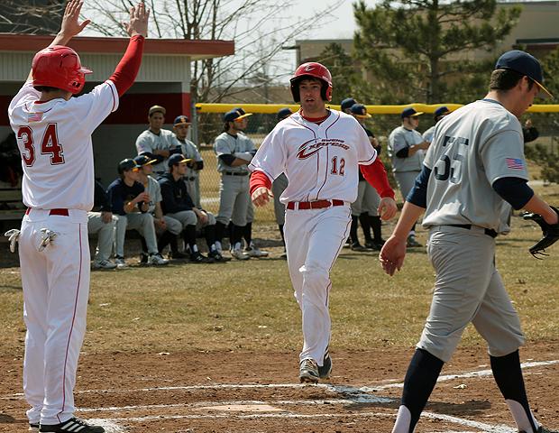 Zach Kazmierski (12) scores on a two-run double by Taran Temple in today's first game. Charlie Sipe (34), who also scored on the plate, greets him at the plate. Photo by Nicholas Huenefeld/Owens Sports Information
